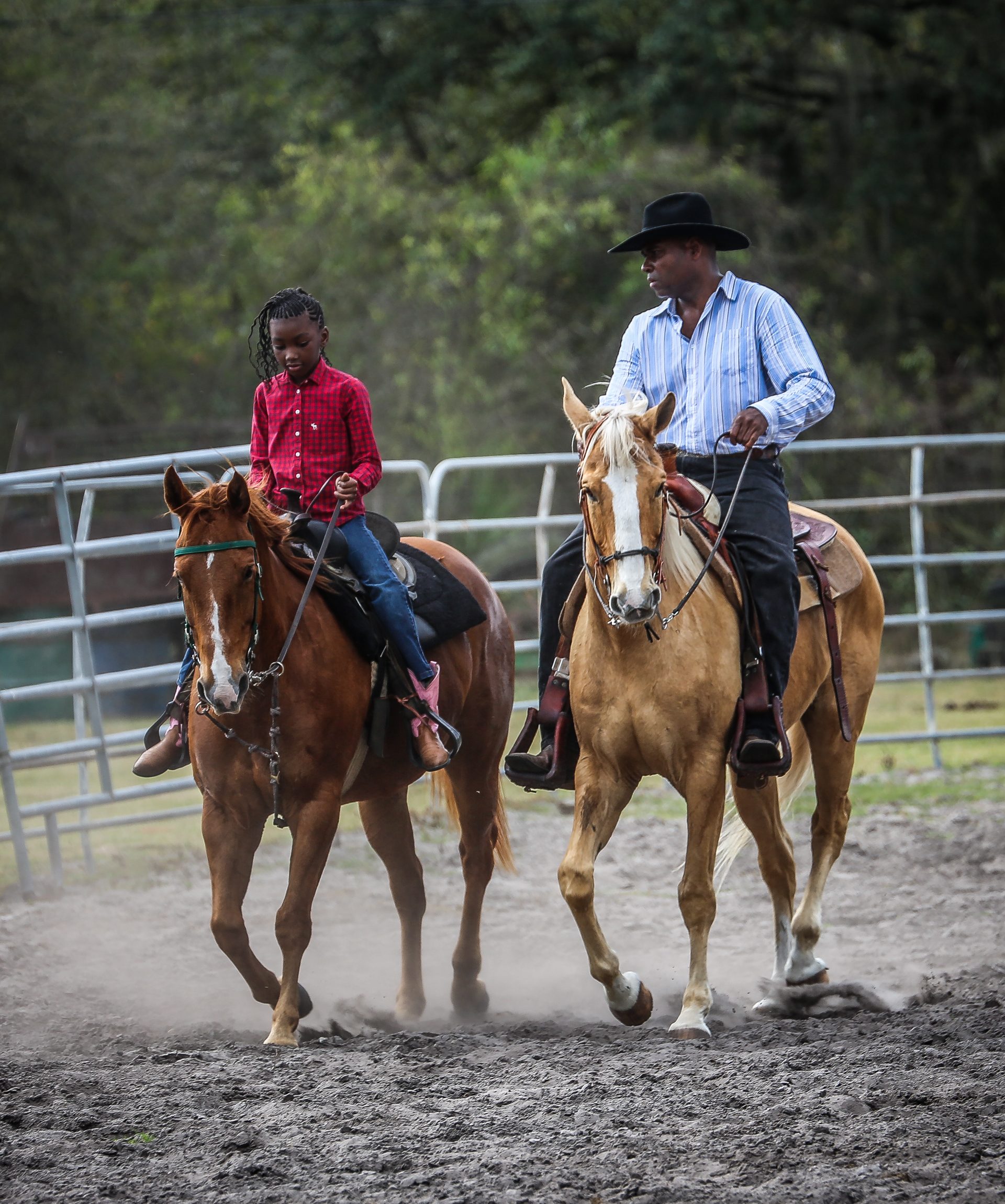 A mentor and young rider on horseback in the arena at Gus Trent Rodeo Association